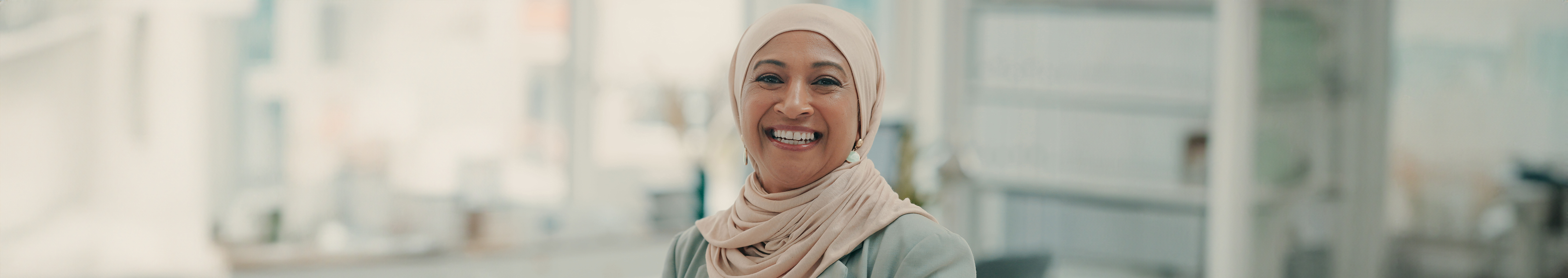 Smiling Arabic woman with cream coloured Hijab top.